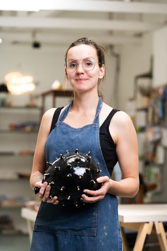 From Colour To Colour to Crafted Clay: A New Chapter in Our Story 2 Nadine Da Silva at Crafted Clay in Johannesburg holding a unique black sculptural pottery piece with metallic spikes.